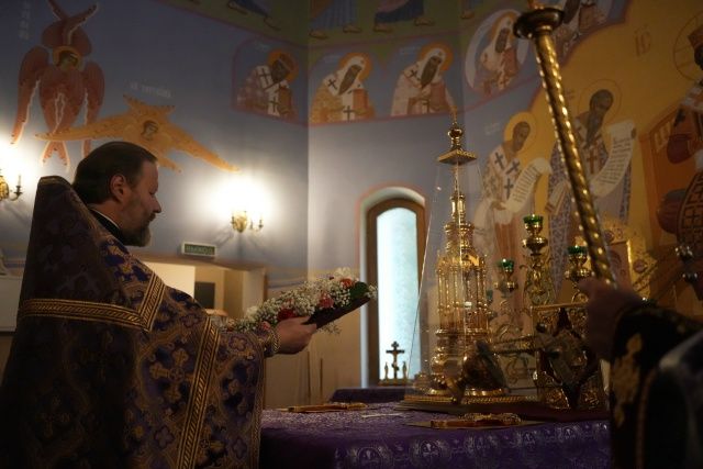 Священнослужитель возносит украшенный цветами Крест