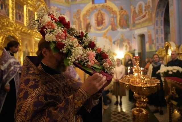 Священнослужитель несёт украшенный цветами Крест